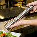 A person holding a Chef Specialties stainless steel pepper mill.