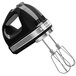 A black and silver KitchenAid hand mixer with stainless steel beaters and a pro whisk.