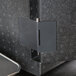 A silver hinge on a black Cambro GoBox on a metal surface.