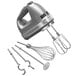 A close-up of a silver KitchenAid 9-speed hand mixer with a wire whisk and other attachments.