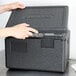 A person's hands opening a black Cambro Cam GoBox.