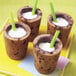 A group of chocolate chip cookie shot glasses with straws filled with milk.