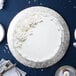 A white cake with white frosting and flowers on a silver Enjay round cake drum on a table.