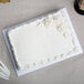 A white frosted rectangular cake on a white Enjay cake board.