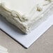 A close up of a white 1/4 sheet cake on a white cake board.