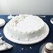 A white cake on a table with a white Enjay round cake drum underneath.