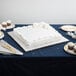A white cake with silver decorations on a silver cake board on a table.