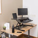 A black Luxor adjustable two-tier standing desk with a laptop and a monitor on it.