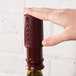 A hand using a Franmara Burgundy Wine Saver vacuum pump bottle stopper to seal a bottle of wine.