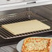 A pizza cooking on an American Metalcraft rectangular pizza stone in an oven.