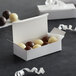 A Baker's Mark white candy box filled with white chocolate candies.