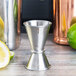 An American Metalcraft stainless steel Japanese style jigger on a table with a lime and lemon.