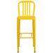 A yellow metal Flash Furniture bar stool with a vertical slat back and legs.