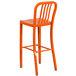 An orange metal bar stool with a vertical slat back.