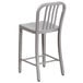 A silver metal outdoor counter height stool with a backrest.