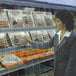 A woman looking at a display cooler of meats with a Curtron strip curtain.