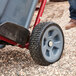 A man uses a Rubbermaid Construction and Landscape Trash Can Dolly to move a grey bucket on a wheelbarrow.