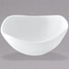 A white bowl with a curved edge on a white surface with a gray background.