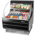 A Turbo Air black low profile horizontal air curtain display case with food inside.