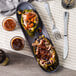 A plate with two stuffed Del Sol Whole Poblano Peppers with meat and vegetables with sauce on a table.