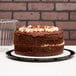 A close-up of a chocolate cake in a D&W Fine Pack cake display container with a clear dome lid.
