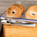 Stainless steel tongs serving a tray of bagels.