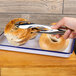 A person using American Metalcraft stainless steel serving tongs to pick up a bagel with a hole in it.