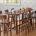 A Lancaster Table & Seating solid wood live edge table top with wine glasses and chairs.