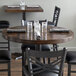 A Lancaster Table & Seating round wood table top with espresso finish on a table with glasses and napkins.