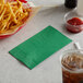 A basket of french fries with a green Choice paper napkin next to a drink.