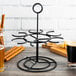 A black metal rack with Vollrath tasting glasses holding beer and snacks on a table.