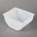 A white square bowl with a lid on a gray surface.