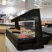 A black Cambro table top buffet with a variety of food on display under a glass cover.