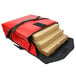 A red Sterno insulated pizza carrier with several pizza boxes inside.
