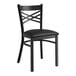 A Lancaster Table & Seating black metal cross back chair with black vinyl cushion.