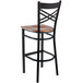 A Lancaster Table & Seating black and wood cross back bar stool with an antique walnut wood seat.