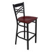 A Lancaster Table & Seating black metal bar stool with a mahogany wood seat.