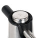 A stainless steel iSi cream whipper with a black button.