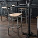 A Lancaster Table & Seating bar stool with a natural wood seat.