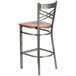 A Lancaster Table & Seating metal bar stool with a cherry wood seat.