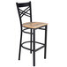 A Lancaster Table & Seating black metal cross back bar stool with a driftwood seat.