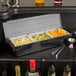 A Choice 3-Compartment Condiment Bar on a counter with containers of fruit and drinks.