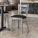 A Lancaster Table & Seating metal chair with black vinyl padding at a table in a restaurant.