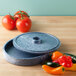 A round blue HS Inc. Polyethylene tortilla server with a lid and tomatoes next to it.