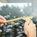 A person holding a Unger brass channel with a gold handle to clean a window.