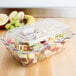 A clear Cambro deli crock with fruit inside.