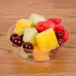 A bowl of fruit in a Fineline Savvi Serve plastic bowl on a table.