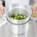 A person using a Vollrath pasta cooker to steam broccoli.