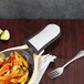 A gray silicone cotton handle cover on a pan with vegetables on a table.