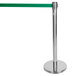 A silver Aarco crowd control stanchion with a green retractable belt.